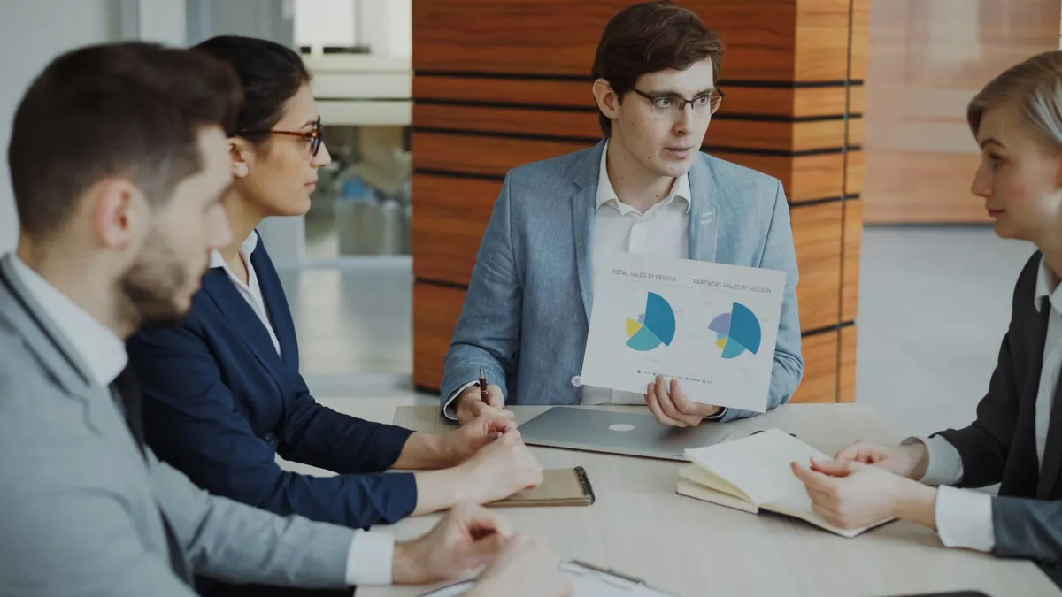 Group of professionals discussing charts during a business meeting.