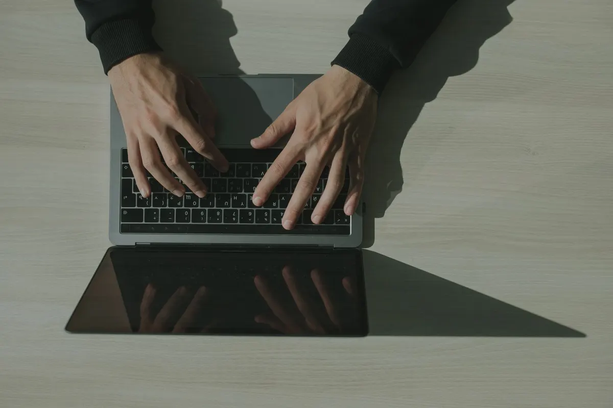 Overhead shot of hands typing on a laptop, showcasing technology and internet usage.