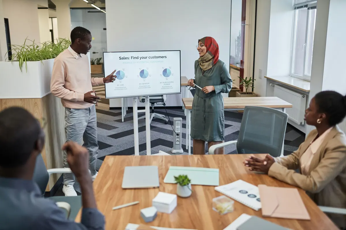 A diverse team engaging in a business meeting focused on sales strategy with visual aids.